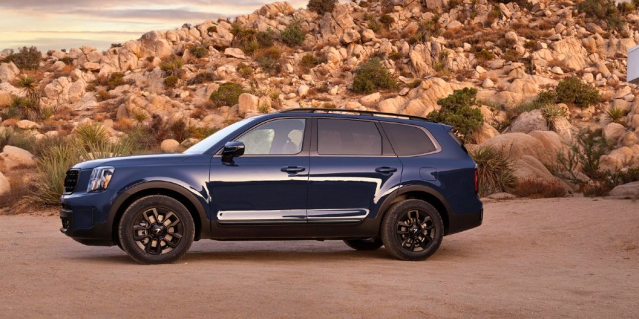 A blue 2024 Kia Telluride midsize three-row SUV is parked (side-view). 