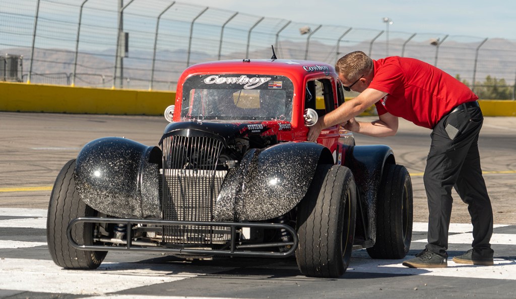 A man from U.S. Legend Car leans into race car to explain to driver on-track technique in Las Vegas