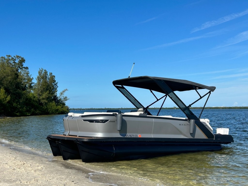 A 22' Manitou Explore pontoon boat sits on the shore in Melbourne, Florida.