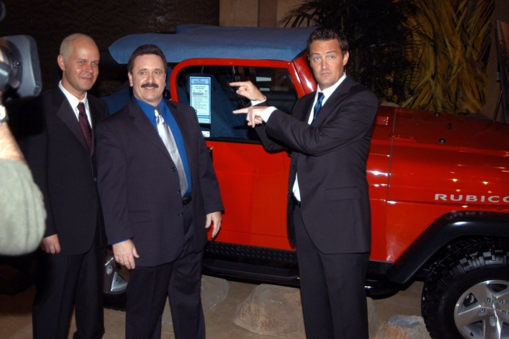 Matthew Perry and company pose beside an off-road car, a Jeep Wrangler TJ Rubicon. 