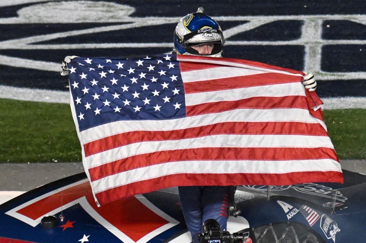 NASCAR driver Justin Allgaier holding the American flag after winning the NASCAR Xfinity Series Alsco Uniforms 300