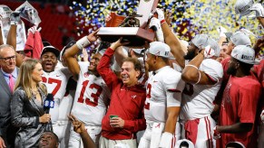 Nick Saban holding the SEC championship trophy with his team, the University of Alabama