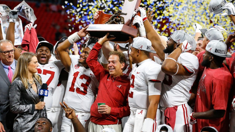 Nick Saban holding the SEC championship trophy with his team, the University of Alabama