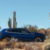 A blue 2023 BMW XM, possibly one of the ugliest cars of 2023, parks next to a cactus.