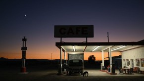 A rural gas station with the lights turned on at dusk.