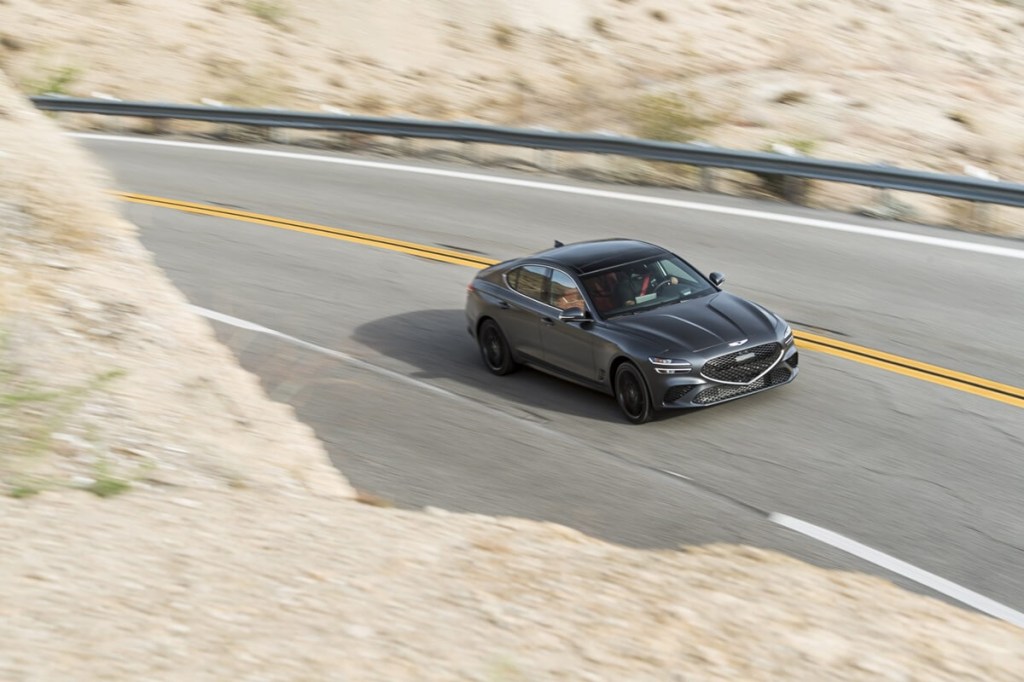 A 2023 Genesis G70 AWD luxury car drives around a corner. 