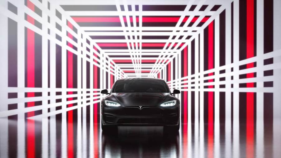 A 2023 Tesla Model S Plaid sits under a plaid-clad motif.