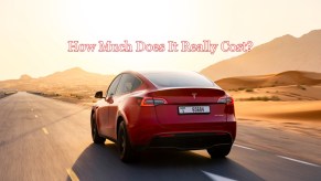 A red Tesla Model Y small electric SUV is driving on the road.