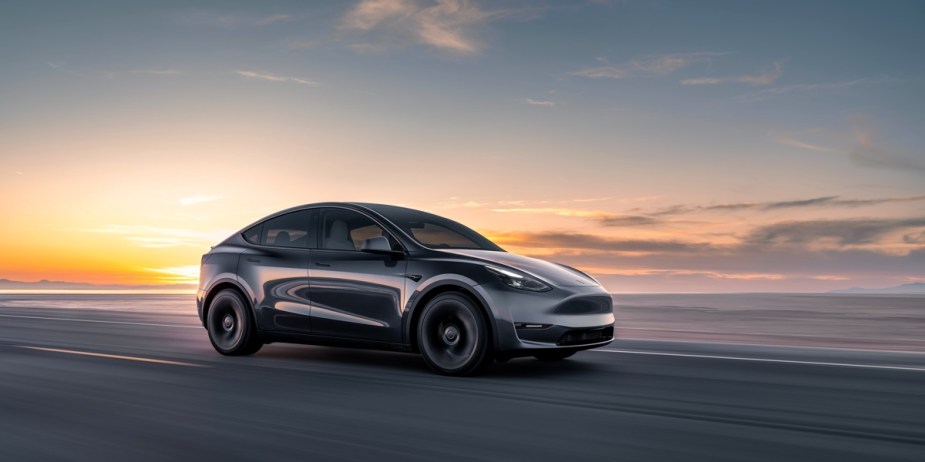 A black Tesla Model Y small electric SUV is driving on the road. 