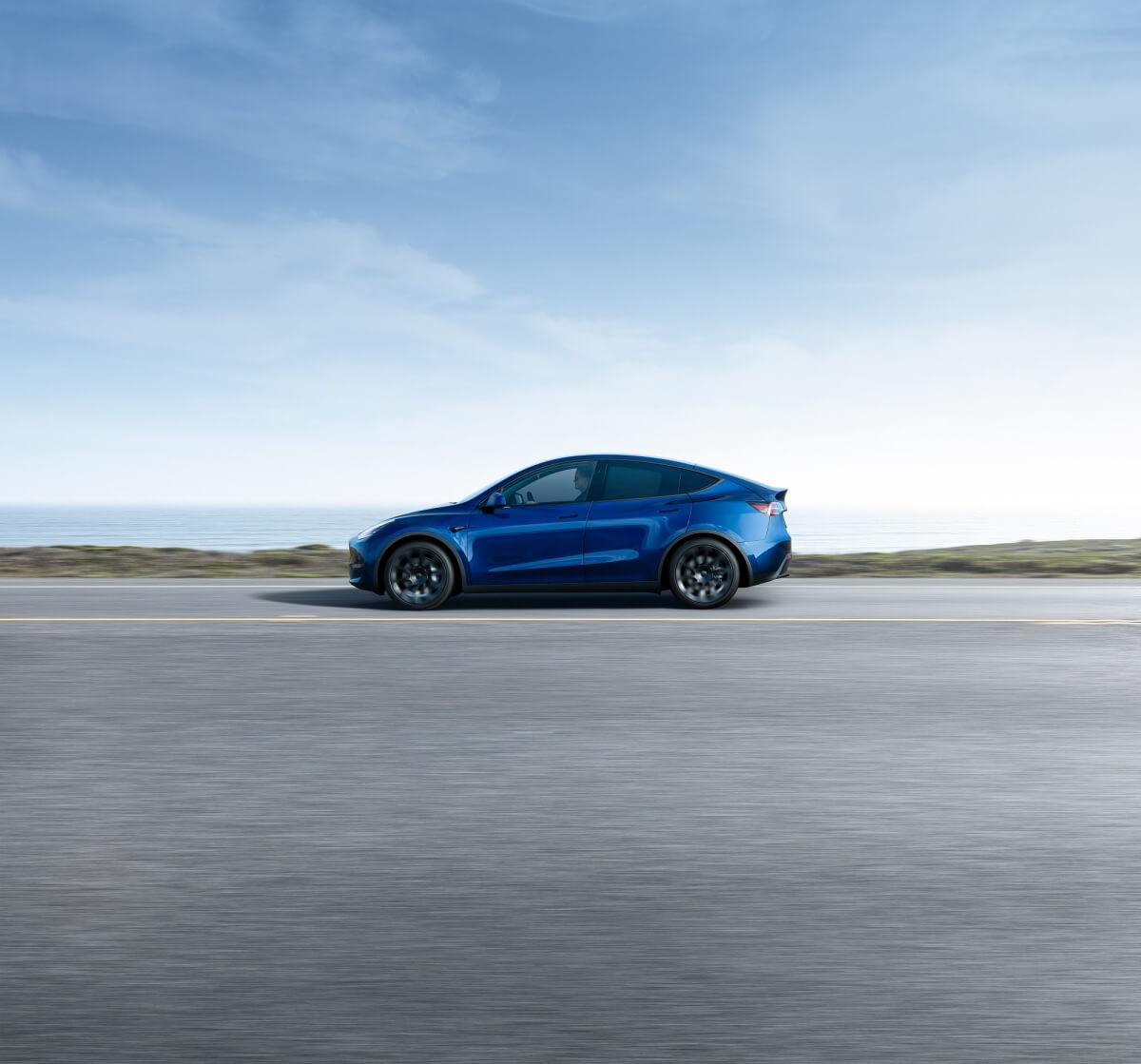 A used Tesla Model Y Long Range in blue cruises an open highway.