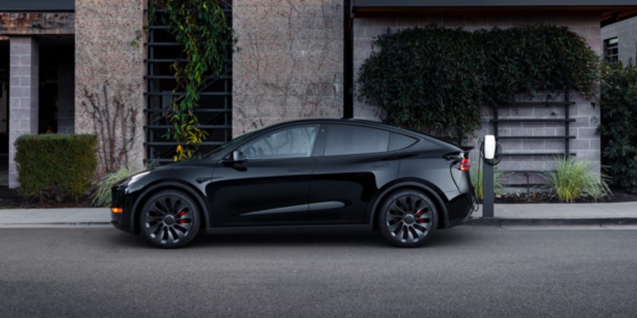A black Tesla Model Y small electric SUV is parked on the road. 