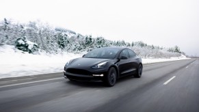 A black Tesla Model 3 driving in the snow. Tesla light shows for Christmas are a bunch of fun
