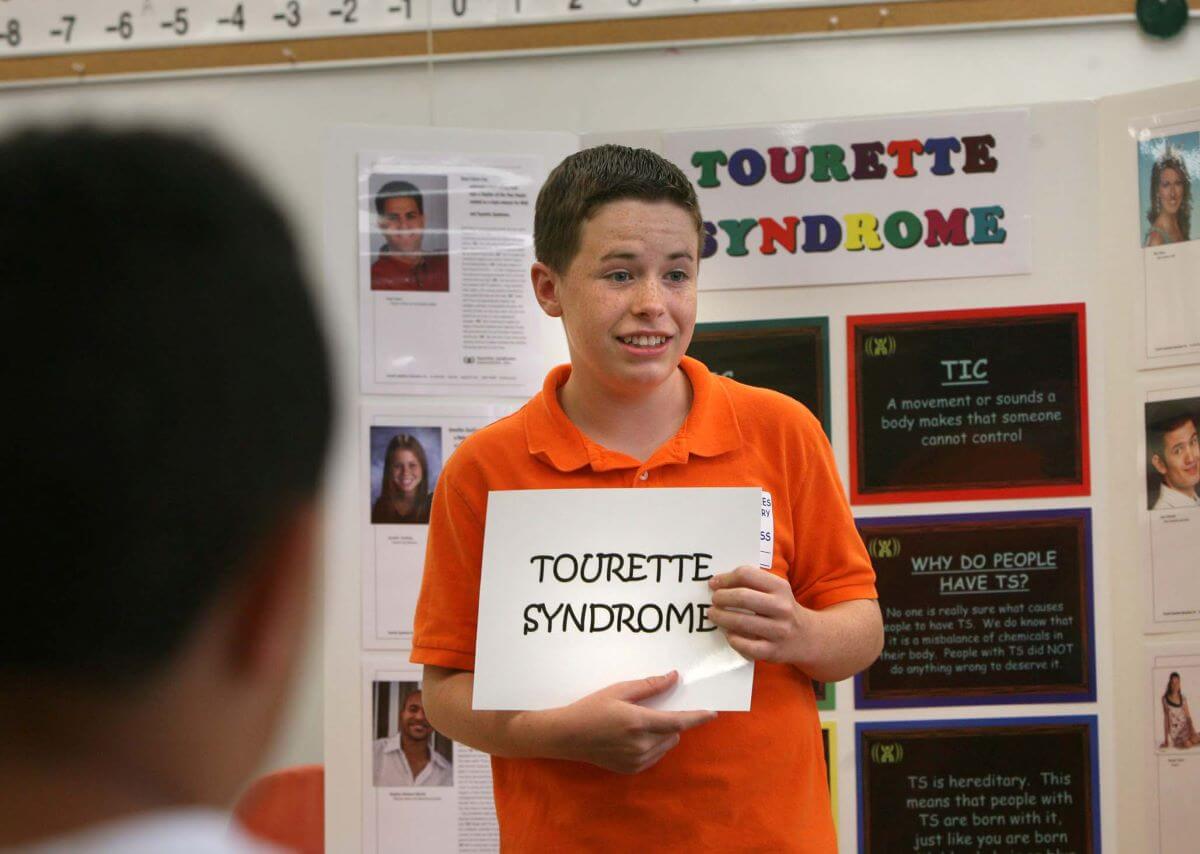 An elementary student with Tourette Syndrome giving a presentation about the condition to his classmates