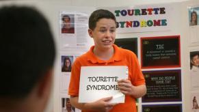 An elementary student with Tourette Syndrome giving a presentation about the condition to his classmates