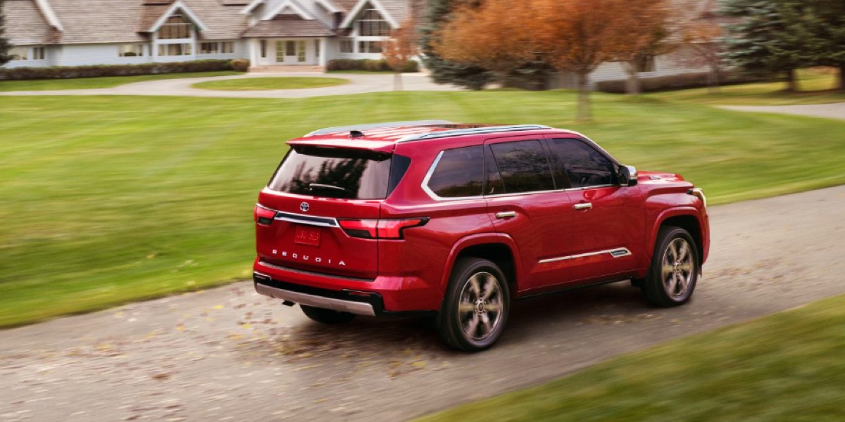 A red 2024 Toyota Sequoia full-size SUV is driving on the road.