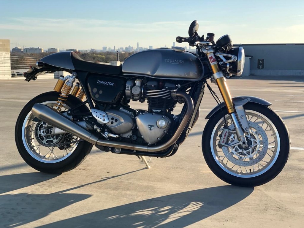 A silver Triumph Thruxton R cafe racer sits on top of an Austin, Texas parking garage.