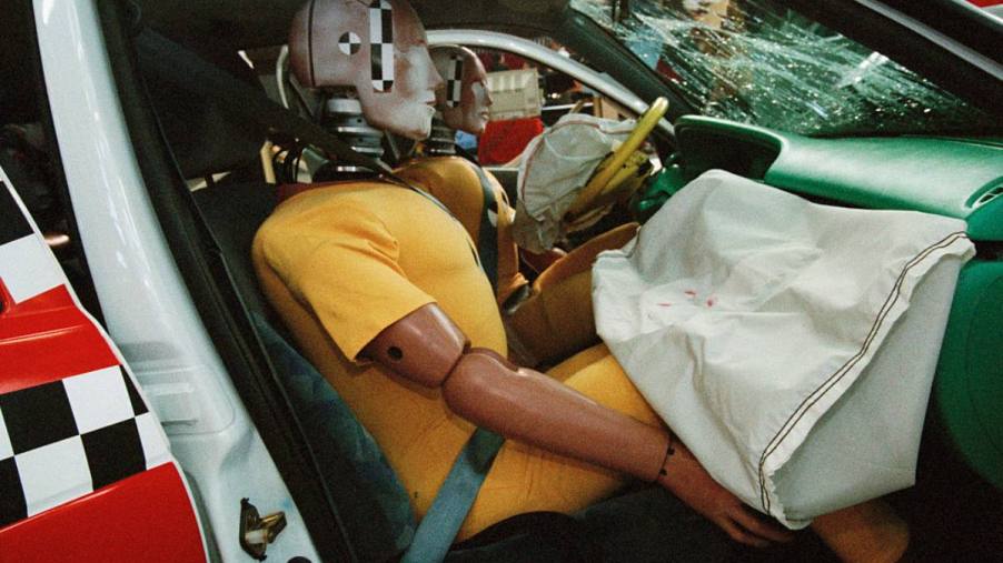 A crash test dummy in the front seat of a truck.