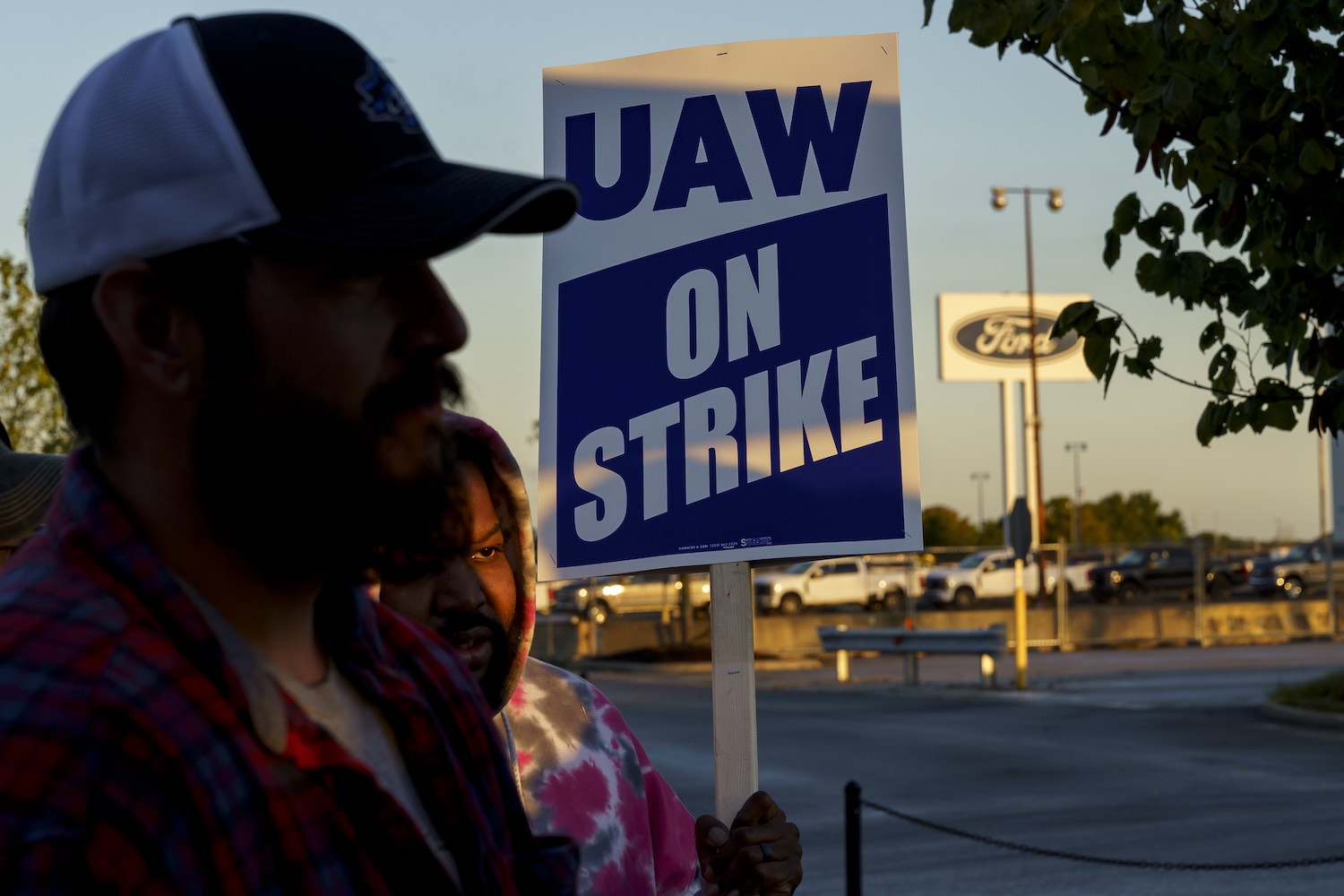 The faces of United Auto Workers Union members holding strike signs outside of Ford's Kentucky plant.
