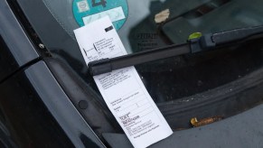 Unpaid parking ticket beneath a windshield wiper.