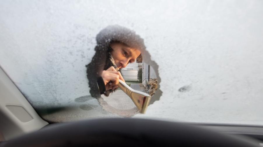 A woman scrapes a frozen windshield