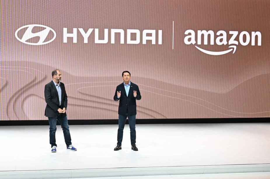 Two Amazon and Hyundai execs talk on stage at the 2023 LA Auto Show with Hyundai and Amazon logos behind them