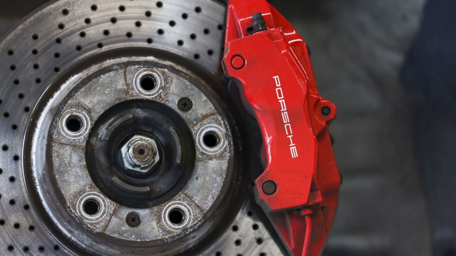 A brake rotor with marks on it and a red Porsche caliper of a Taycan EV sports car model