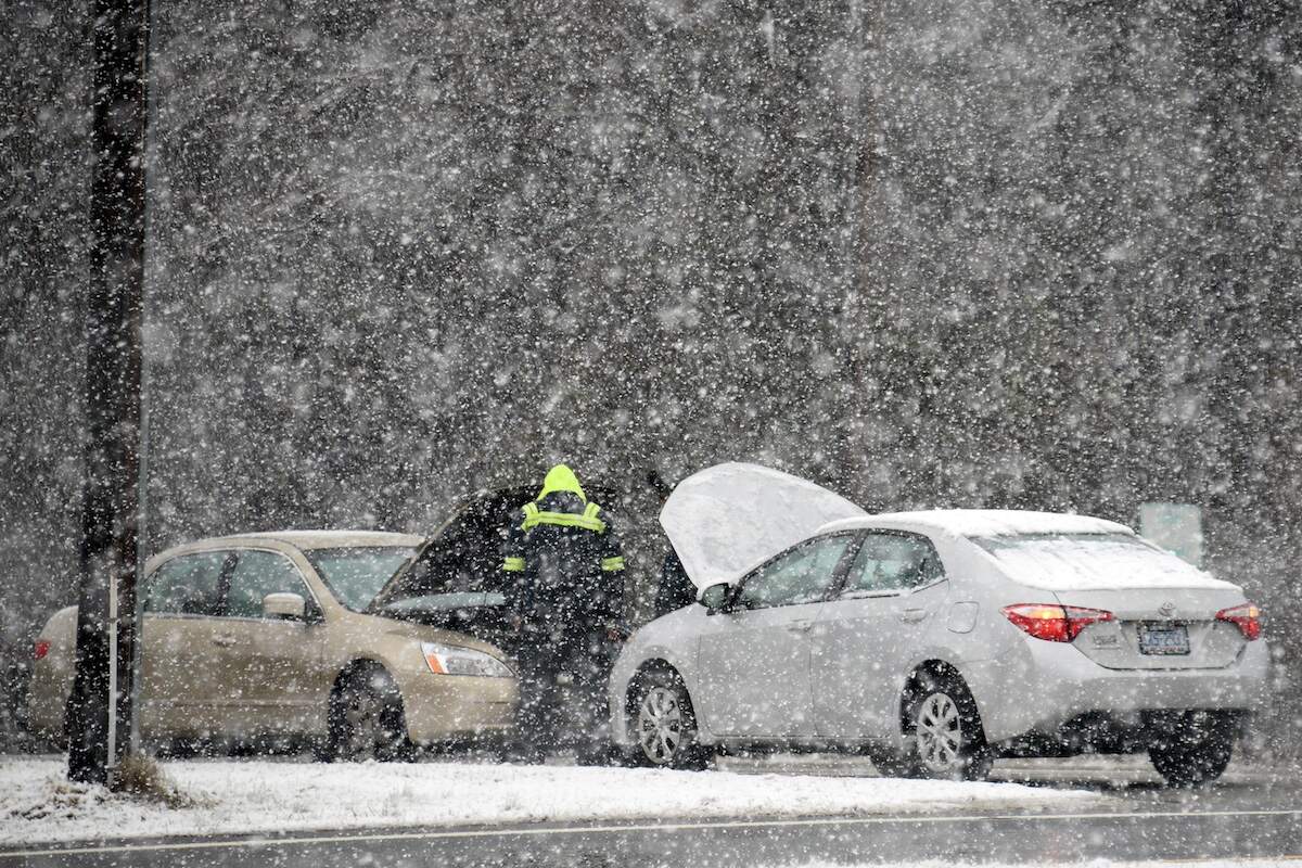 Car battery warmer: A person helps jump a car battery as snow falls