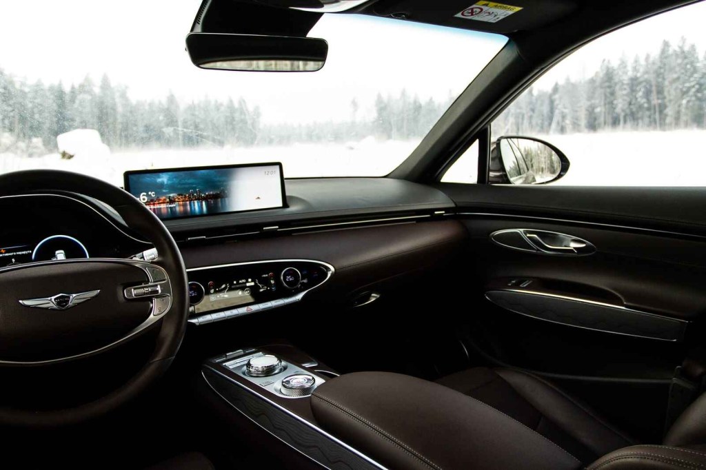 A car infotainment system is shown inside a MINI Cooper with black leather interior parked in winter weather