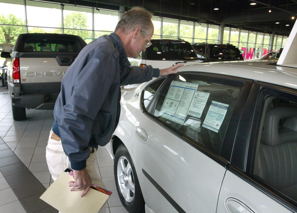 A customer looks at a window sticker in a dealership