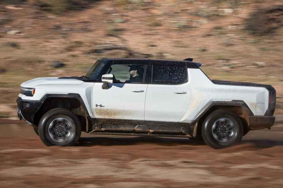 A white Hummer EV Pickup drive in left profile view off-road in desert-like terrain