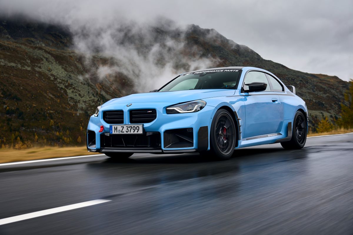 A 2024 BMW M2 subcompact executive sports car model with new performance parts driving on a country highway