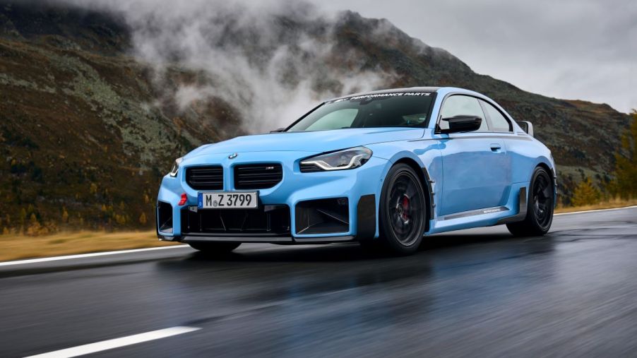 A 2024 BMW M2 subcompact executive sports car model with new performance parts driving on a country highway