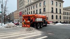 A sanitation department truck spreading road salt and and on city car roads