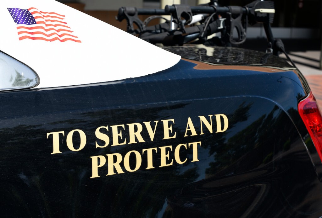 The "Serve and Protect" sign on a cop car