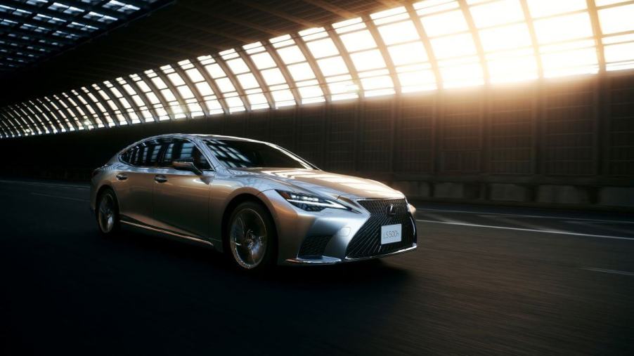 A 2024 Lexus LS 500h full-size hybrid luxury sedan model driving through tunnel with light leaking in