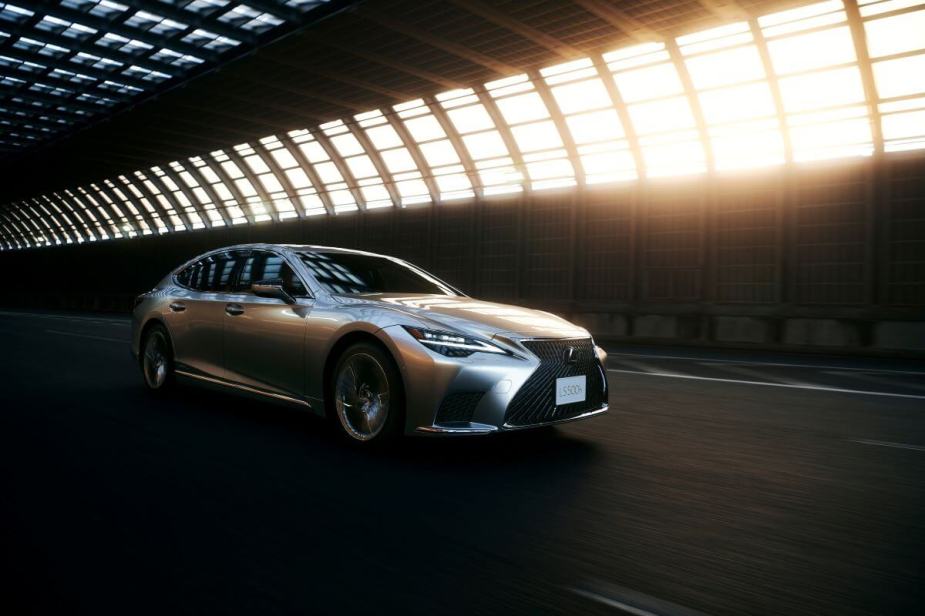 A 2024 Lexus LS 500h full-size hybrid luxury sedan model driving through tunnel with light leaking in
