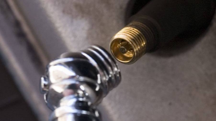 A tire pressure gauge near to a stem valve of a car tire for testing of air pressure and potential leaks
