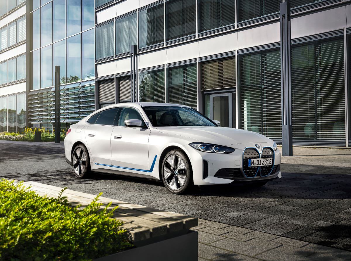 A BMW i4 eDrive40 all-electric luxury sedan model parked on a black tile plaza road