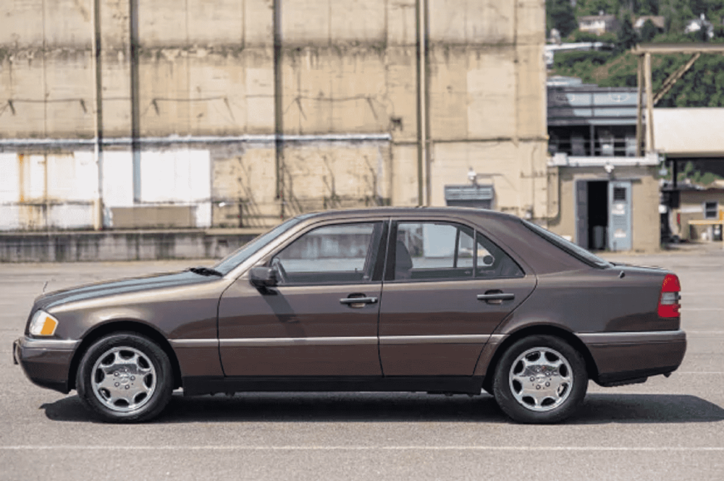 A brown 1994 Mercedes C280 sedan is shown in full left profile view in a parking lot
