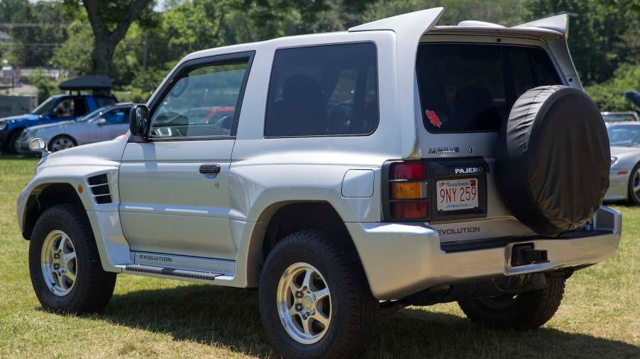 The rear of a silver Mitsubishi SUV parked in a field
