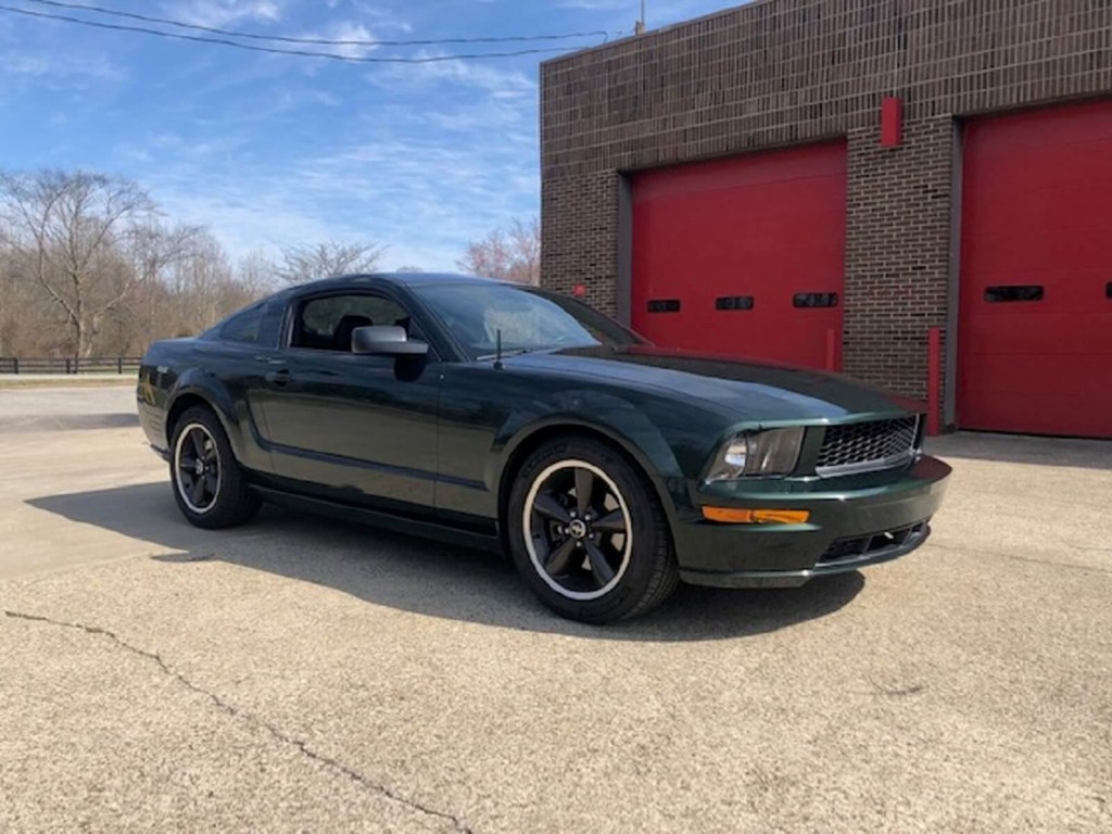 A Dark Highland Green 2008 Ford Mustang Bullitt, like the one in 'Superstore,' sits next to a firehouse.