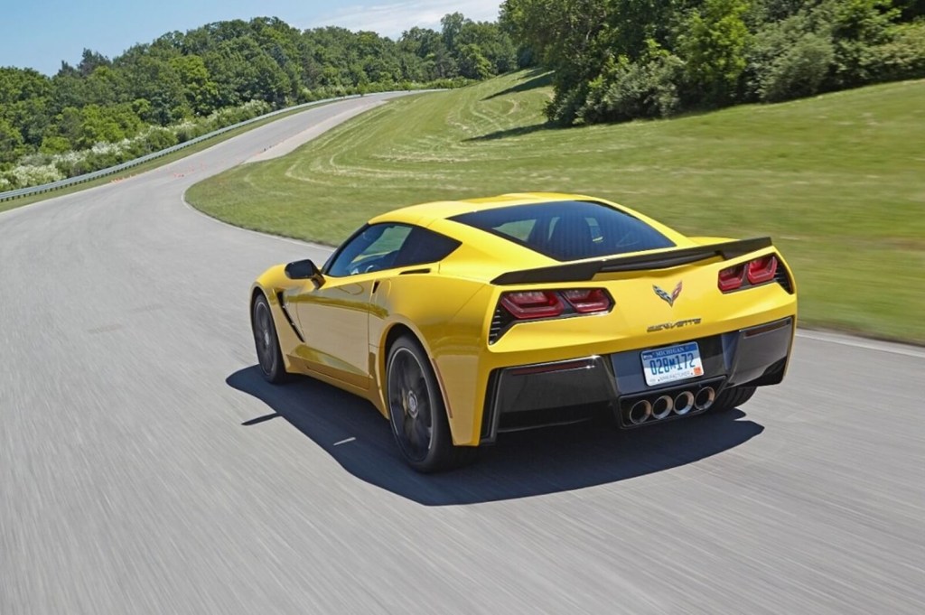 A yellow 2015 Chevrolet Corvette C7 Stingray drives around a corner. 