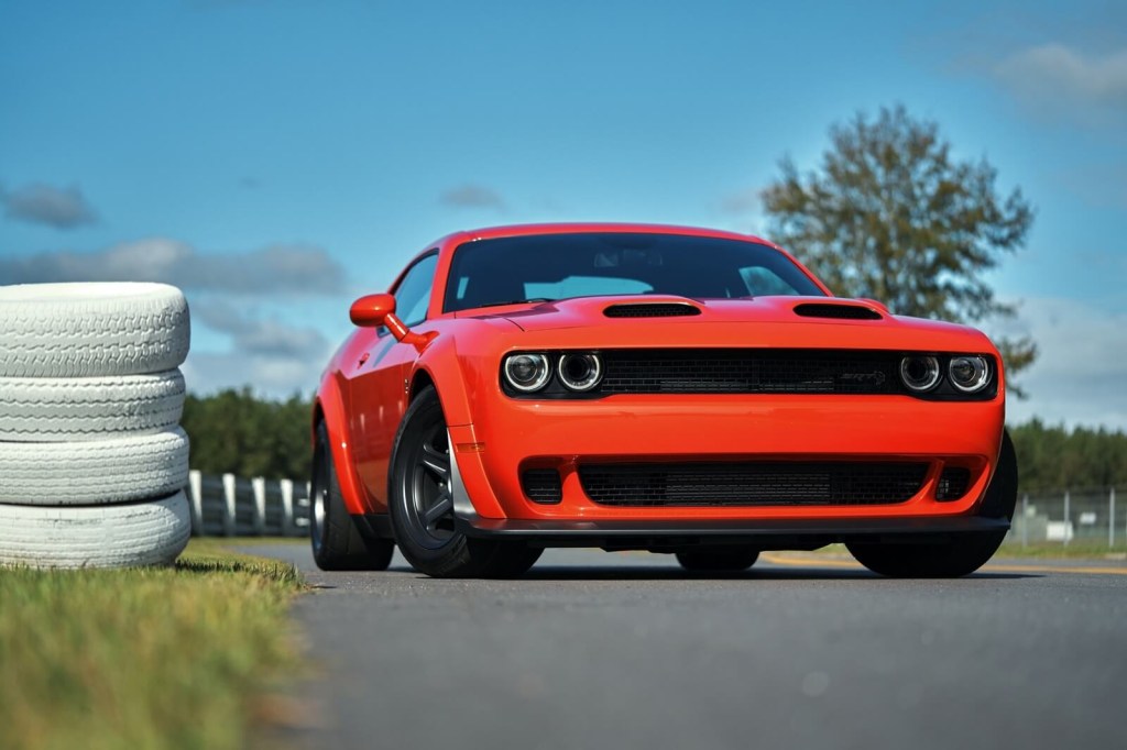 A Dodge Challenger SRT Hellcat Redeye shows off its muscle car fascia by a tire wall. 
