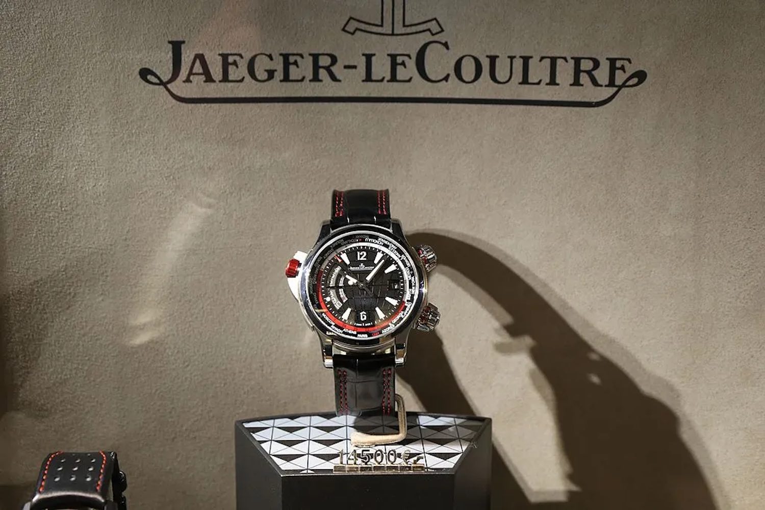 An Aston Martin series watch on display beneath a Jaeger-LeCoultre sign.