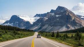 A truck drives toward the Rocky Mountains in Canada