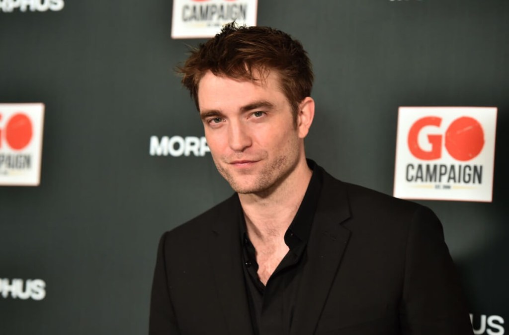 Robert Pattinson, a celebrity who doesn't car about cars, poses for a picture at an event for celebrities.