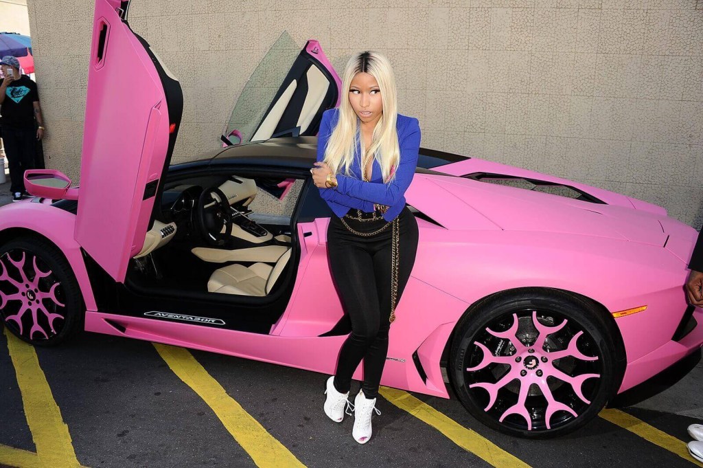 Nicki Minaj poses with her pink Lamborghini Aventador at an event. 