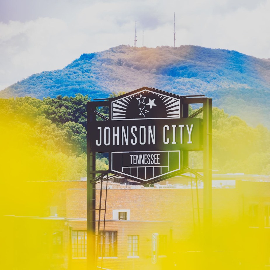 Sign for Johnson City, Tennessee, beneath a mountain ridge.