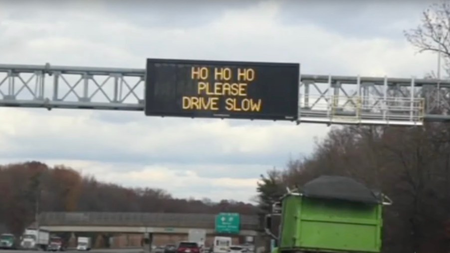 A Road sign above the New Jersey highway that reads "Ho Ho Ho Please Drive Slow"