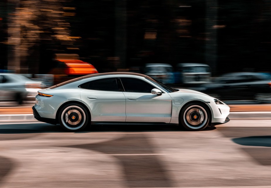 Four-door Porsche Taycan electric sports sedan driving down a busy street.